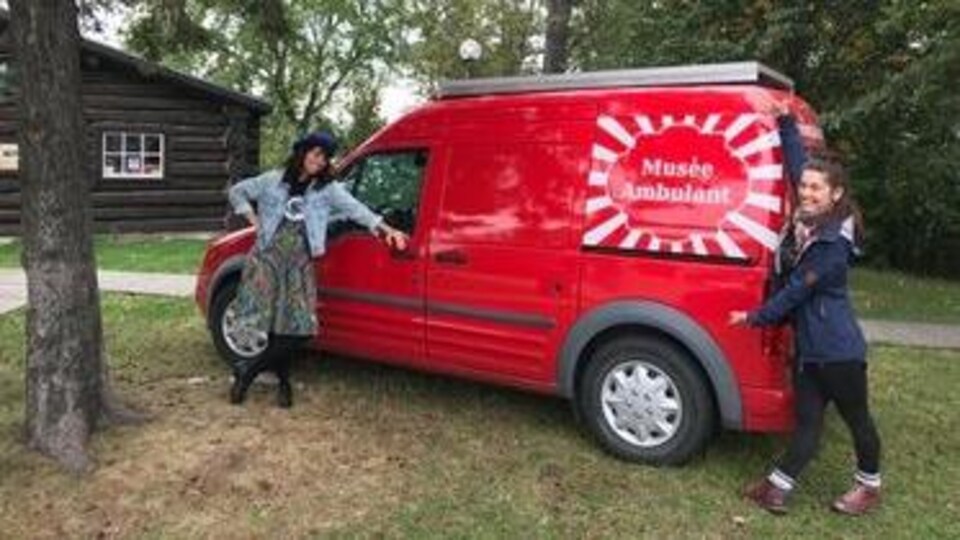 Deux femmes posent fièrement près d'un véhicule coloré du Musée Ambulant.