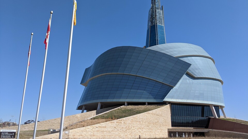 Le Musée canadien des droits de la personne vu de l'extérieur à côté de drapeaux. 