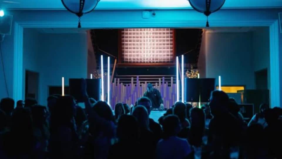 Une soirée de Chiaroscuro au musée des beaux-arts de Montréal, on voit un DJ mixer et des jeunes danser devant.