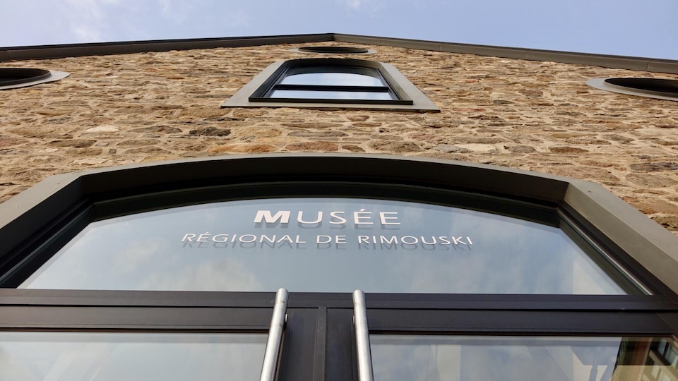 Enseigne en haut d'une porte du Musée régional de Rimouski avec son nom inscrit sur la vitre.