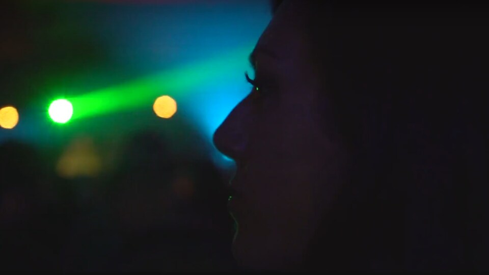 Une femme de profil dans une salle de spectacle.