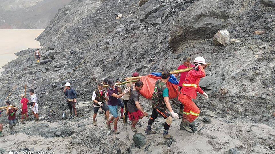 Des sauveteurs transportent le corps d'une victime d'un glissement de terrain au Myanmar.