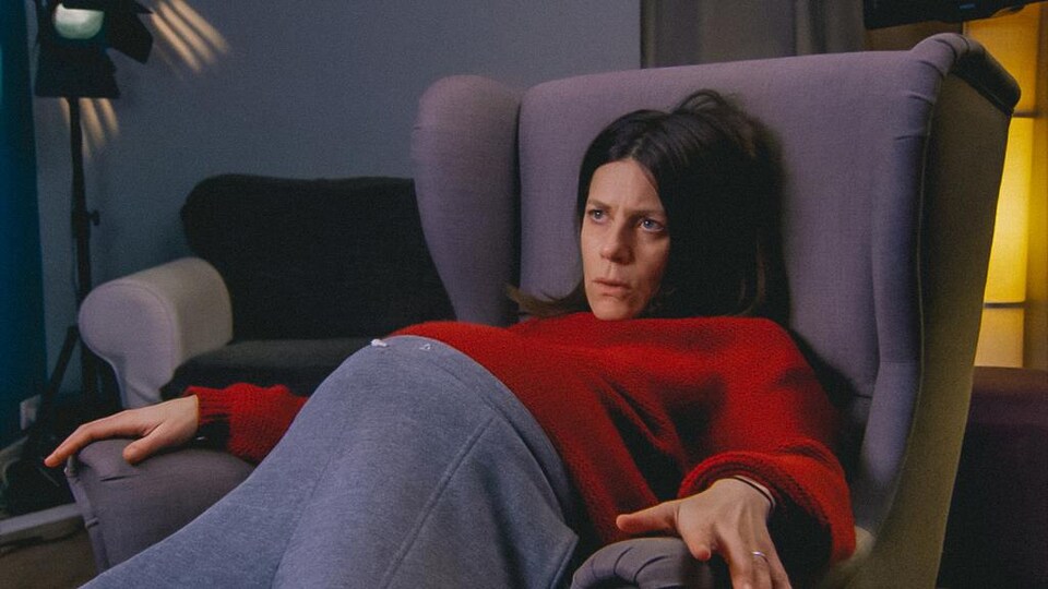 Une actrice enceinte est assise dans une chaise, l'air découragé.