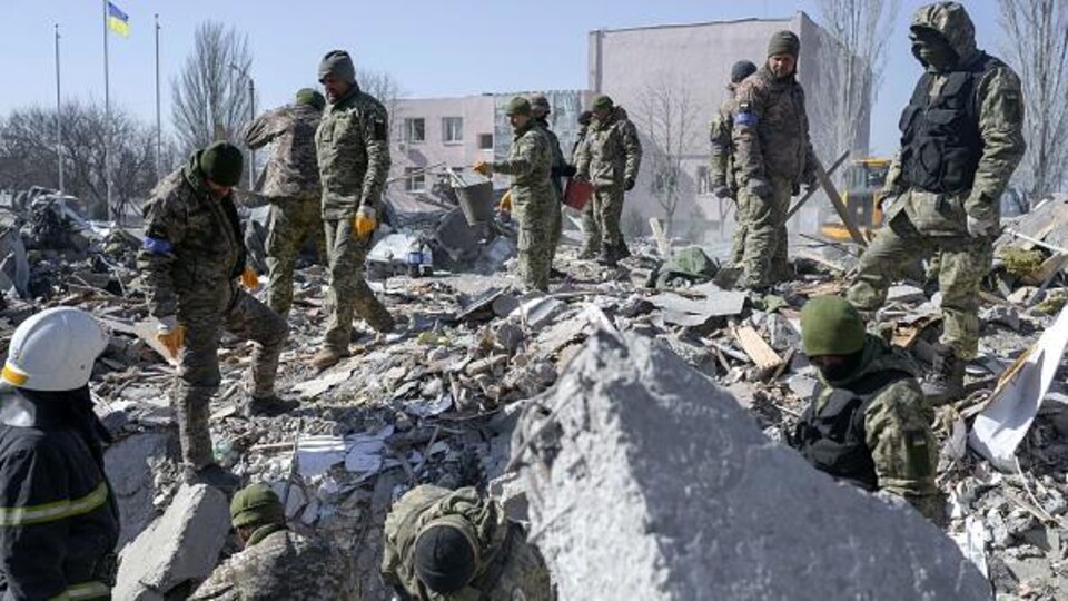 Des soldats ukrainiens recherchent des corps sous des décombres.