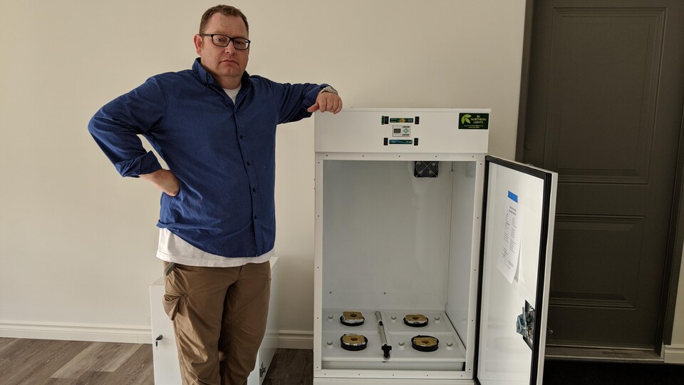 Un homme se tient debout à côté d'une machine ressemblant à un réfrigérateur programmable.