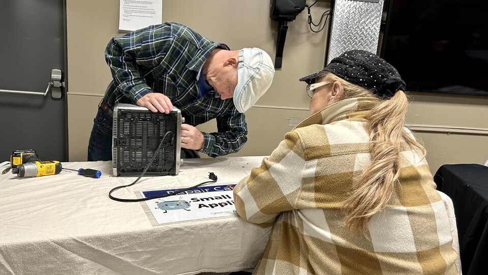 Myrna Lickiss qui regarde le réparateur qui essaie de réparer son grille-pain au Repair Cafe à Okotoks en mars 2023.