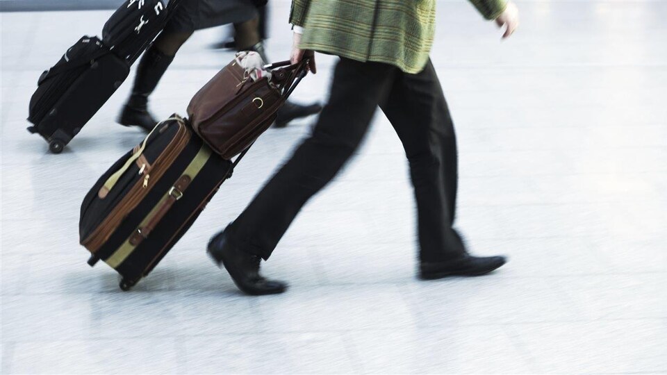 Deux personnes marchent avec des valises sur un plancher d'aéroport.