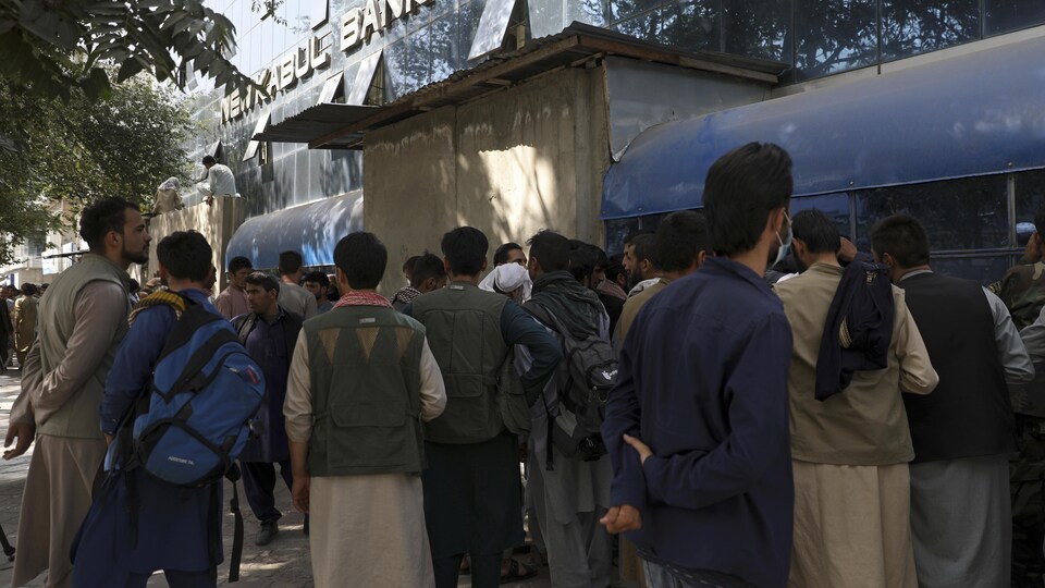 Des Afghans font la queue devant une banque de Kaboul.