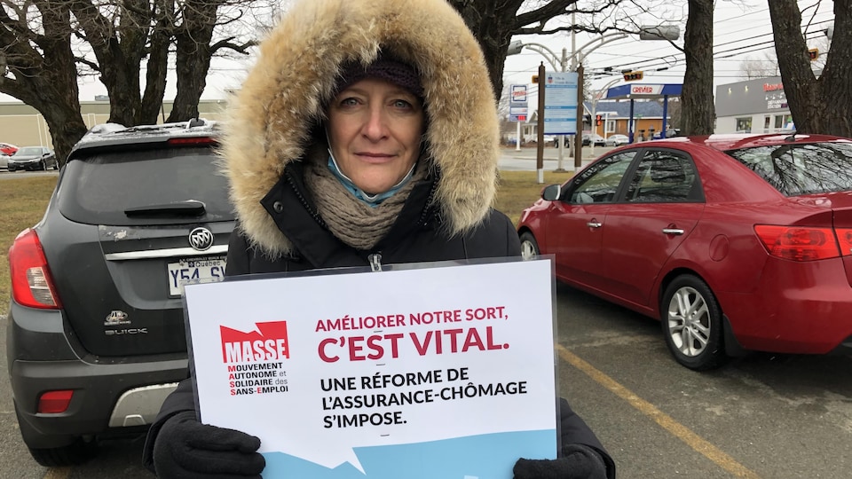 Nadia Mongeon tient une pancarte où on peut lire : Améliorer notre sort, c'est vital. Une réforme de l'assurance-chômage s'impose.