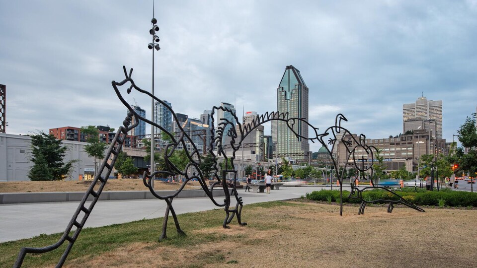 Une partie de la sculpture. Au loin, on voit les gratte-ciels du centre-ville de Montréal.