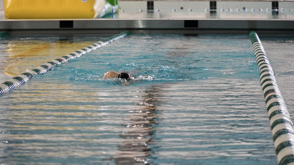Un nageur à l'entraînement dans un corridor de natation.