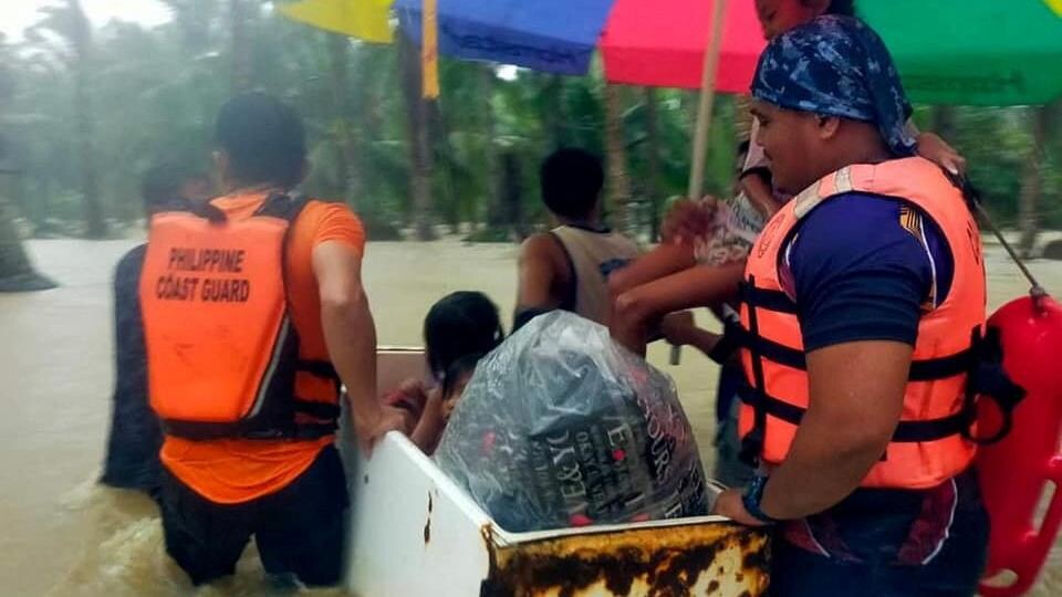 Des sauveteurs de la garde côtière philippine et des habitants utilisent un réfrigérateur cassé comme bateau de fortune. 