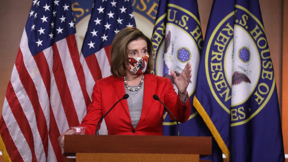 Nancy Pelosi, masquée, à une tribune.