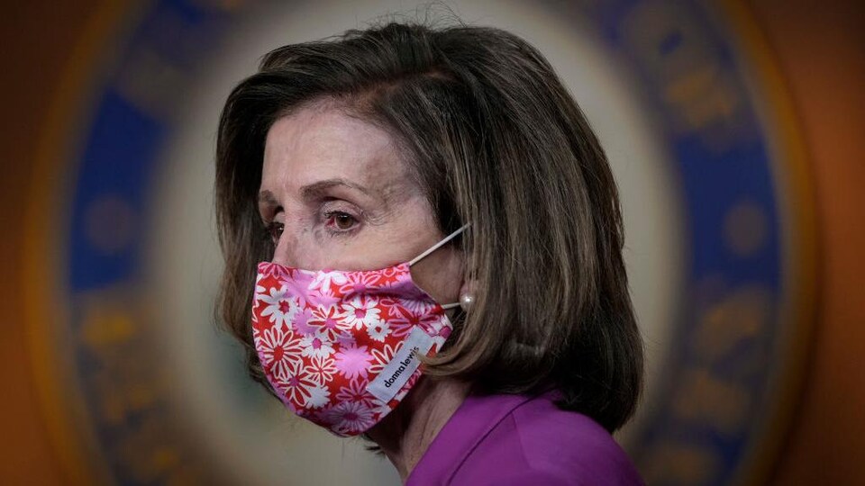 De profil, Nancy Pelosi porte un masque en tissu fleuri.