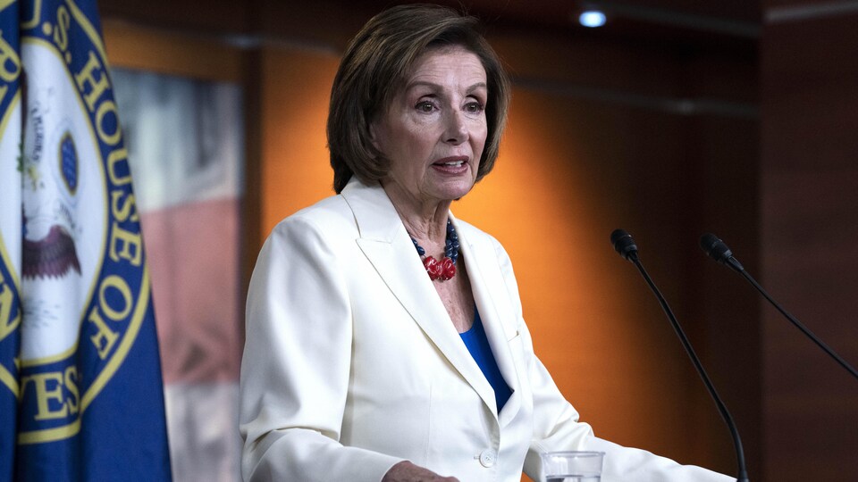 Nancy Pelosi est debout et écoute.