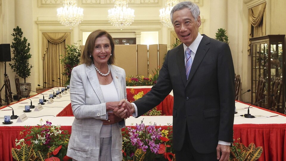 Nancy Pelosi serre la main de Lee Hsein Loong dans une salle de conférence à Singapour.