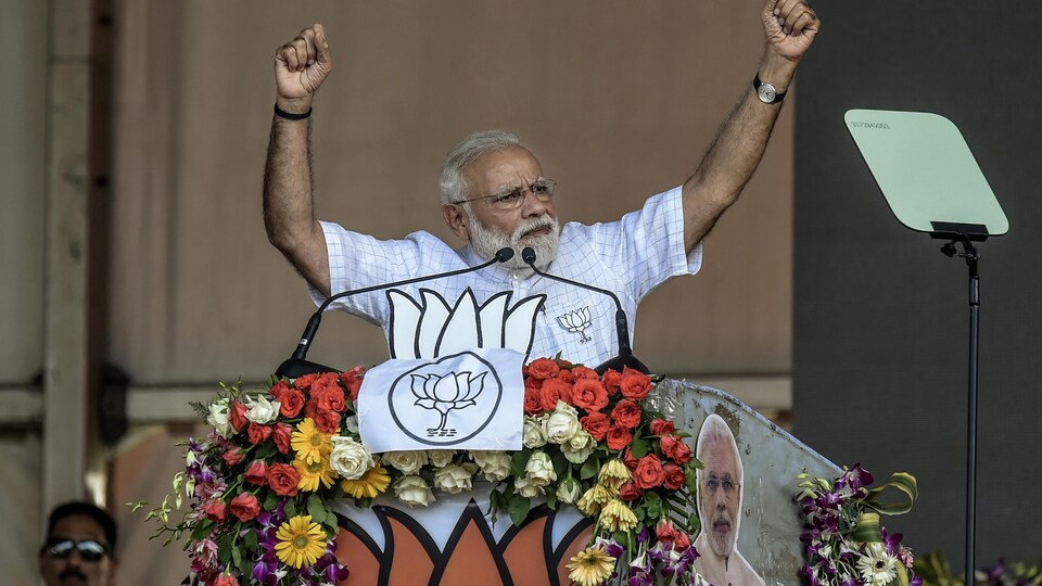 Narendra Modi soulève les bras en s'adressant à la foule.