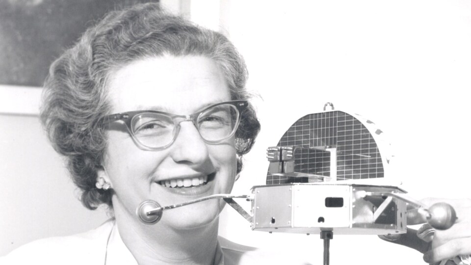 Nancy Grace Roman pose à côté d'un modèle de l'Orbiting Solar Observatory, en 1962.