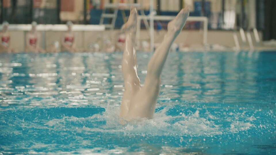 Des jambes d'une nageuse artistique émergent de l'eau
