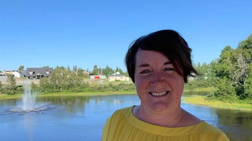Une femme tout sourire posant devant un lac