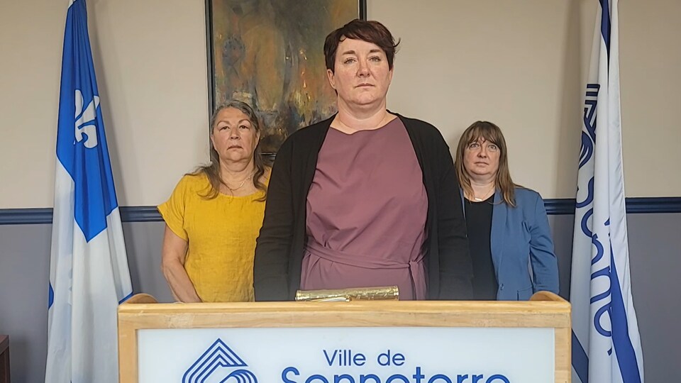 Three women stand behind a lectern.