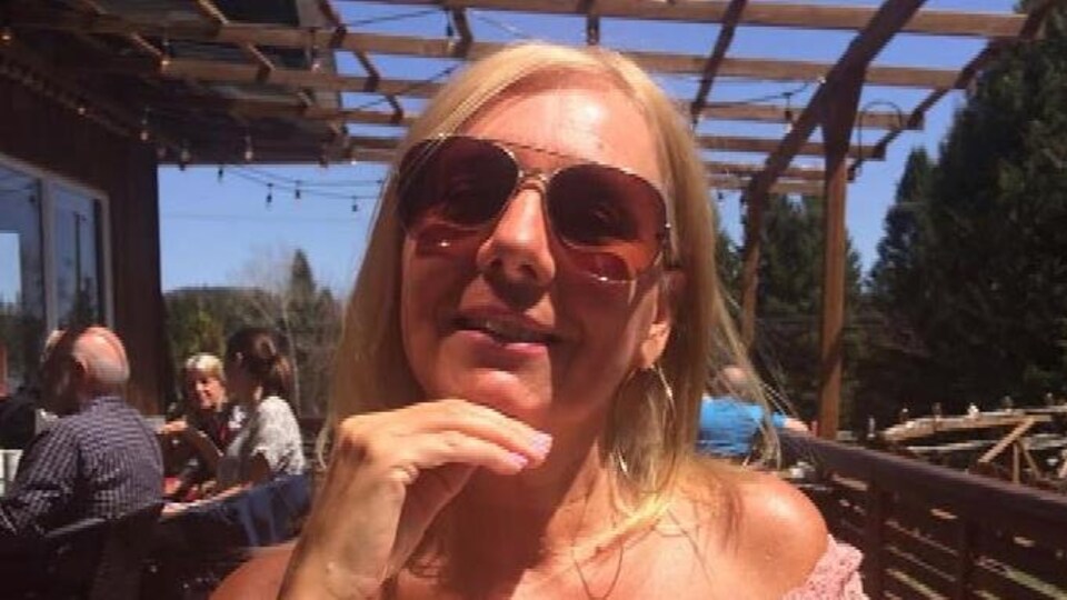 Une femme souriante en vacances, assise à une table.