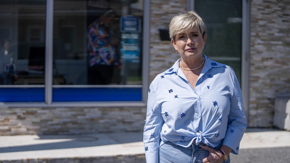 Nathalie Simard, dressed in blue, poses in front of the building.