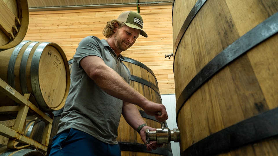 Nathan Kohlert checks a barrel containing beer. 