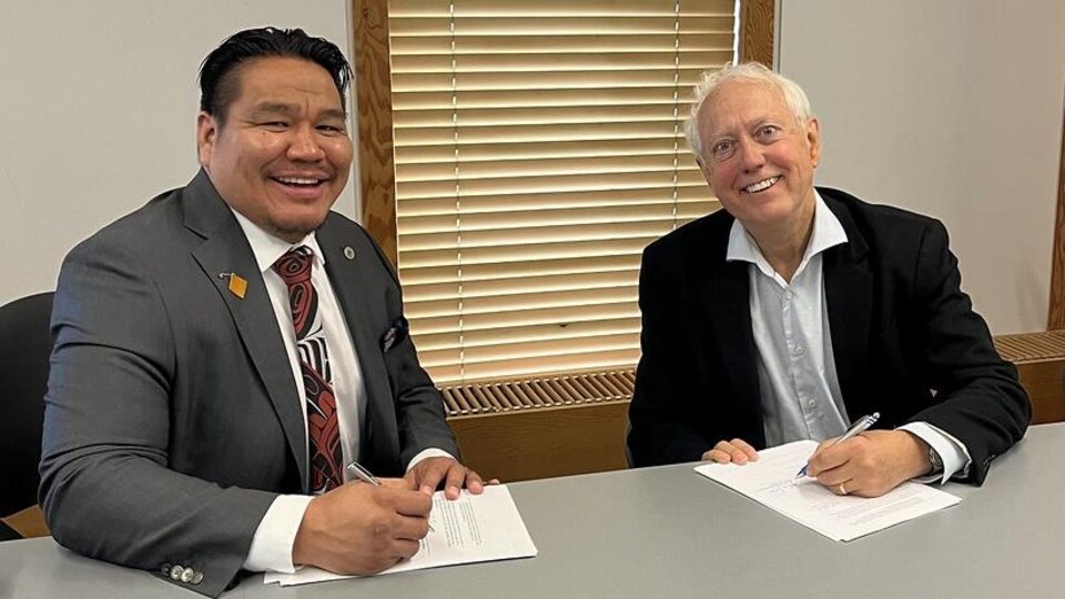 Murray Rankin, ministre des Relations avec les Autochtones et de la réconciliation et Murphy Abraham, chef de la Nation Lake Babine, sont assis à une table et signent l 'accord.