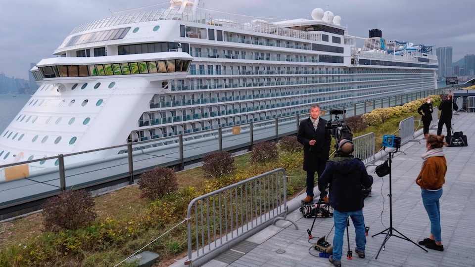 Deux équipes de journalistes de la télévision s'activent, sur la terre ferme, à proximité du navire de croisière World Dream.