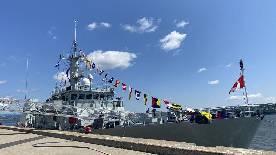 Le NCSM Glace Bay, un navire de défense côtière, transporte plusieurs drapeaux, dont celui du Canada à la proue. 