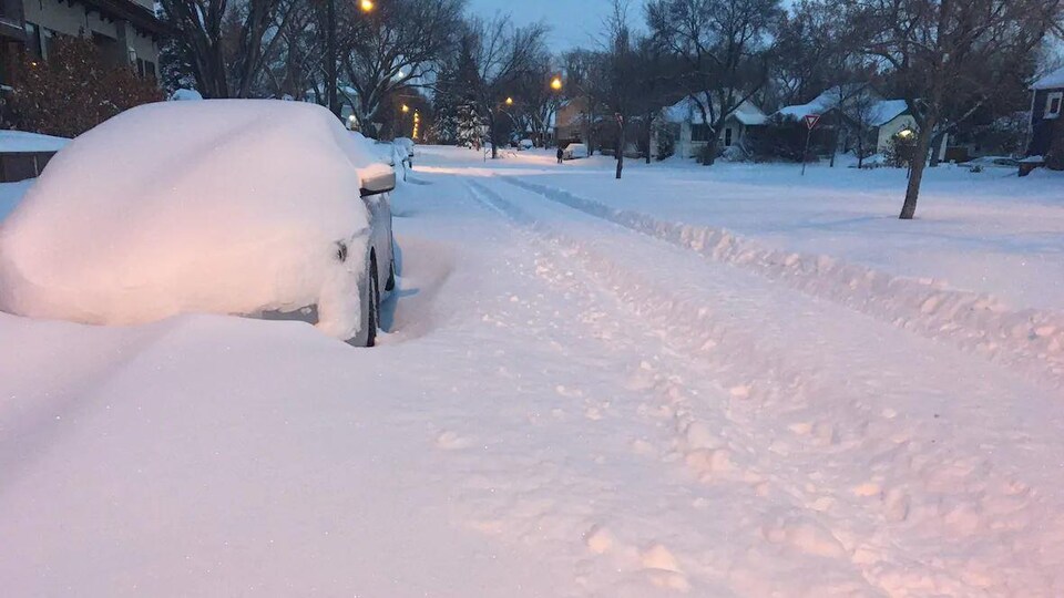 Une voiture ensevelie sous la neige fraîchement tombée à Saskatoon.