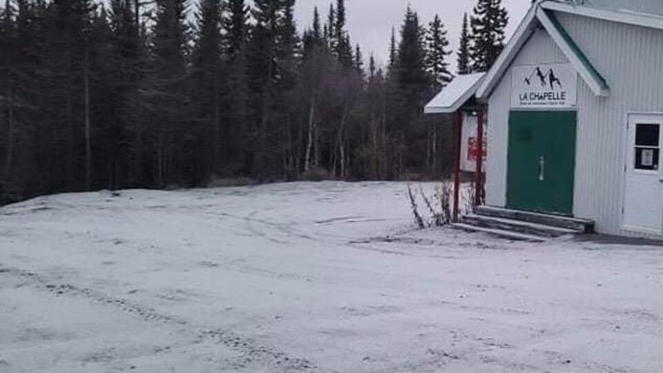 Un relais pour les motoneigistes est recouvert d'une fine couche de neige.