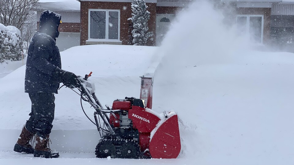 Un homme passe la souffleuse dans la neige.