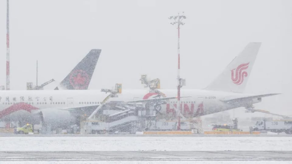 As the snow continues to fall, a snow plane is on the ground.