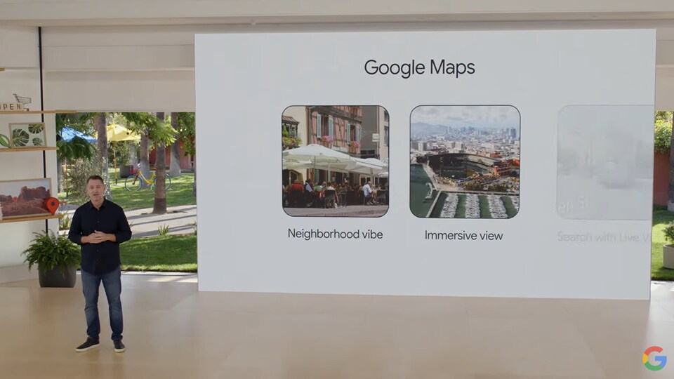 Un homme présente deux fonctions de Google Maps à côté d'un écran géant. 