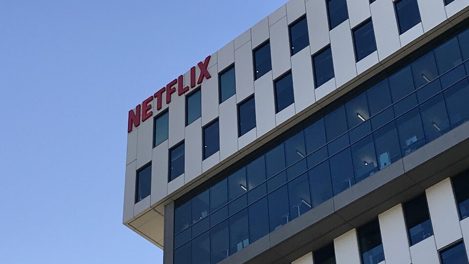 Un immeuble avec le logo de Netflix vu en contre-plongée sur un ciel bleu.