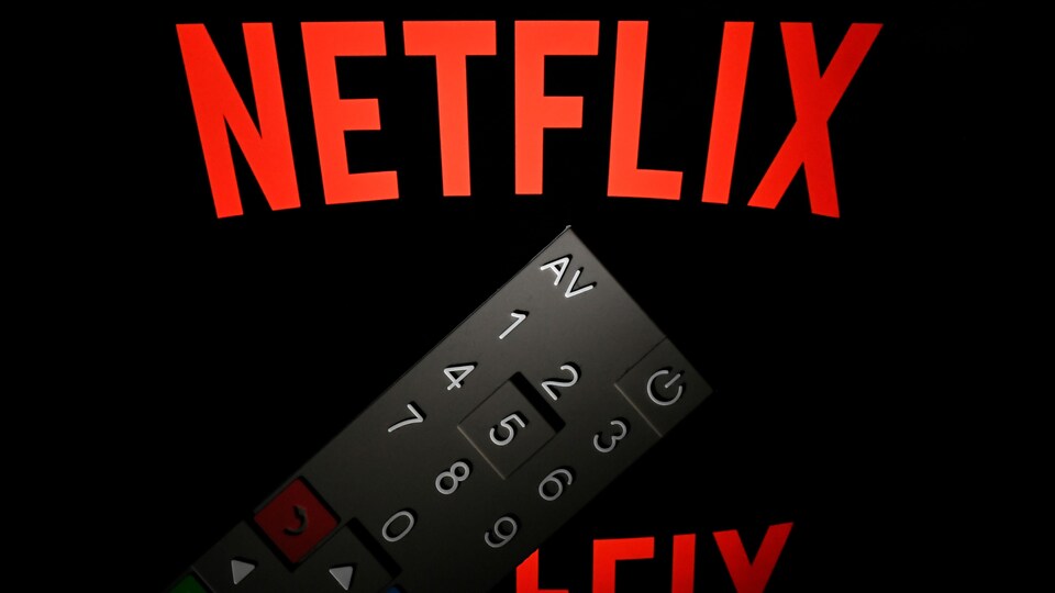 Une télécommande de télévision devant le logo de Netlix.