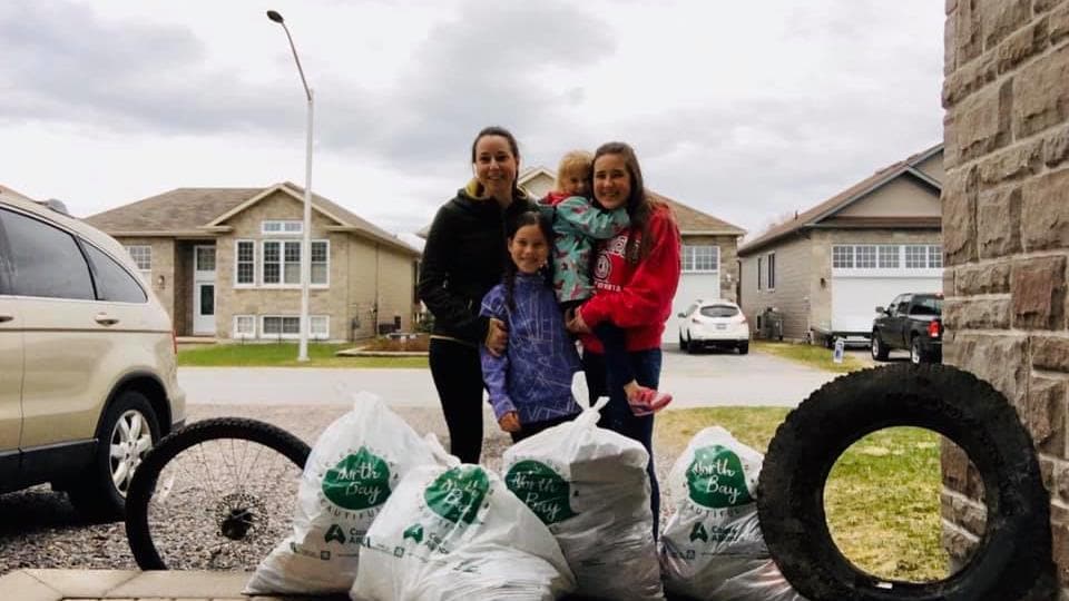 Une mère et ses 3 enfants montrent les sacs remplis d'ordures qu'elles ont ramassées.