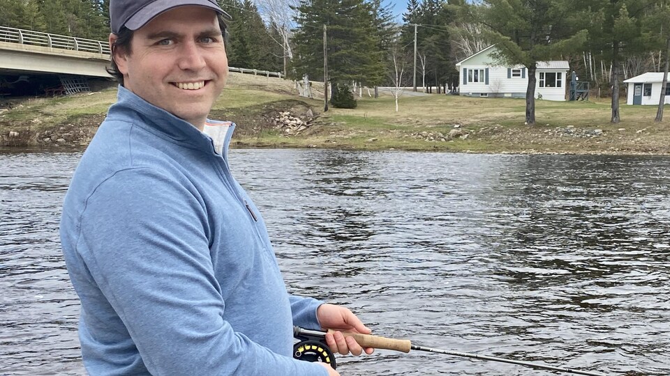 Neville Crabbe tient sa canne à pêche en bordure de la rivière Miramichi.