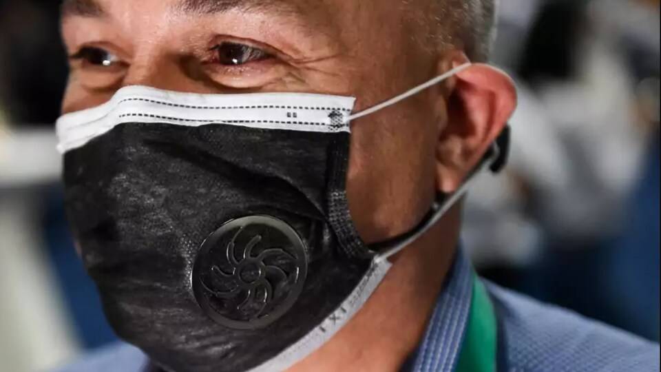 Un homme porte un masque muni d'un petit ventilateur. 