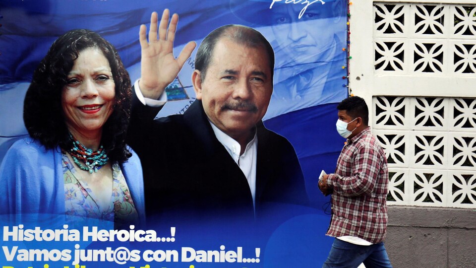 Un homme passe devant une affiche électorale montrant un homme et une femme.