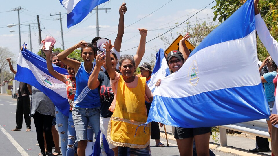 Des Nicaraguayens brandissent des drapeaux et lèvent les bras pour démontrer leur joie.
