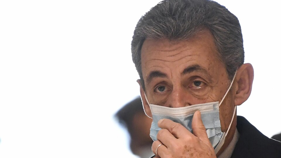 L'ancien président français Nicolas Sarkozy ajuste son masque facial le dernier jour de son procès pour corruption, le 10 décembre 2020 au palais de justice de Paris.