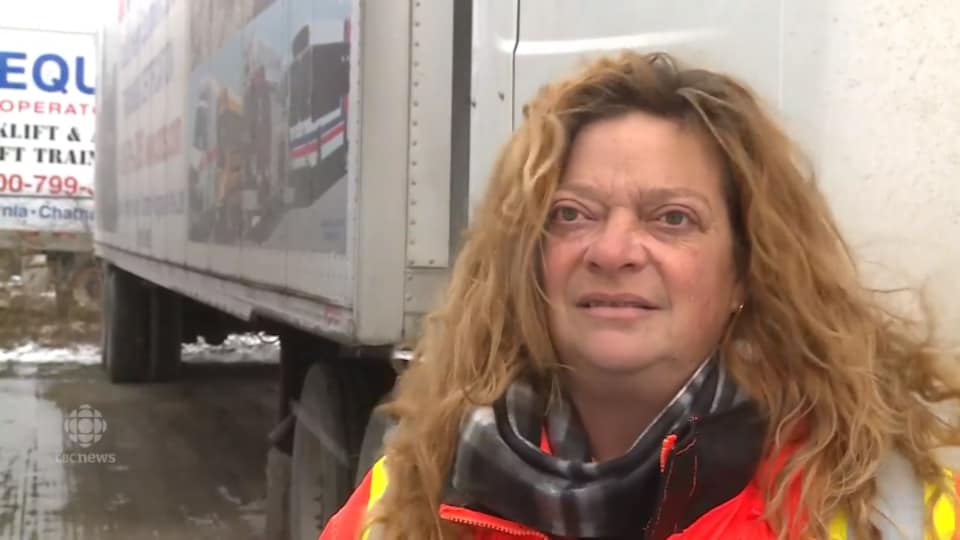 Une femme parle au micro d'un journaliste devant un camion.