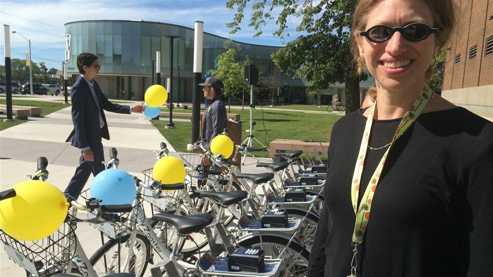 Une femme est photographiée devant des vélos. 