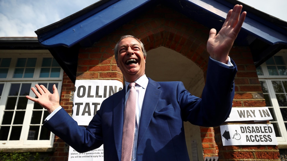 Nigel Farage, tout sourire, devant un bureau de vote.