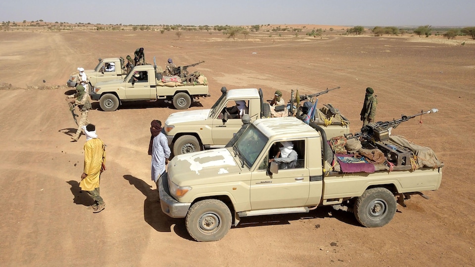 Des hommes et des véhicules munis d'armes dans le désert.