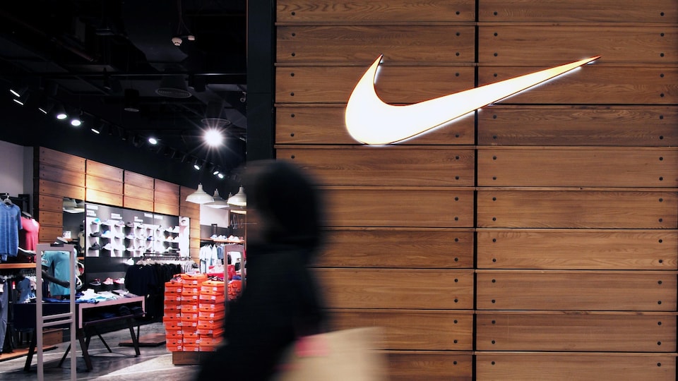 une dame passe devant le fameux logo de Nike à l'entrée d'une boutique à Manama, au Bahreïn