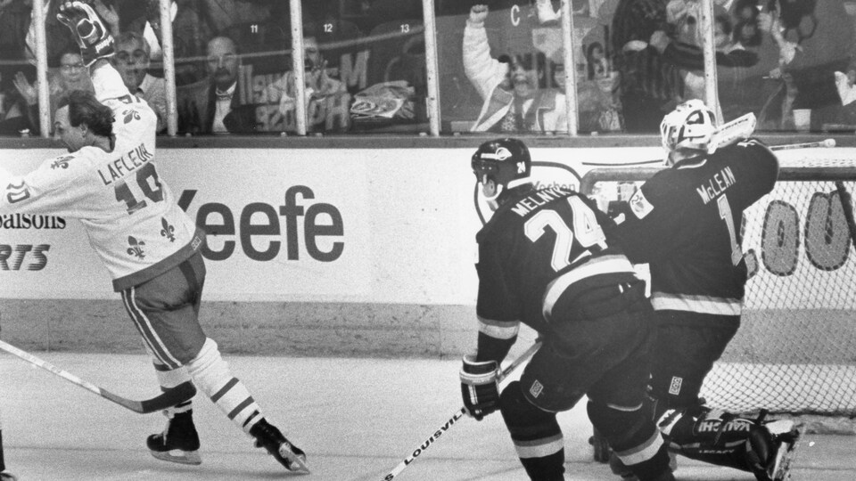 Guy Lafleur vient de marquer pour les Nordiques lors d'un match contre les Canucks de Vancouver au Colisée, en novembre 1989. Il file en levant le bras en l'air en signe de victoire, alors que les Canucks derrière peinent à suivre le rythme.